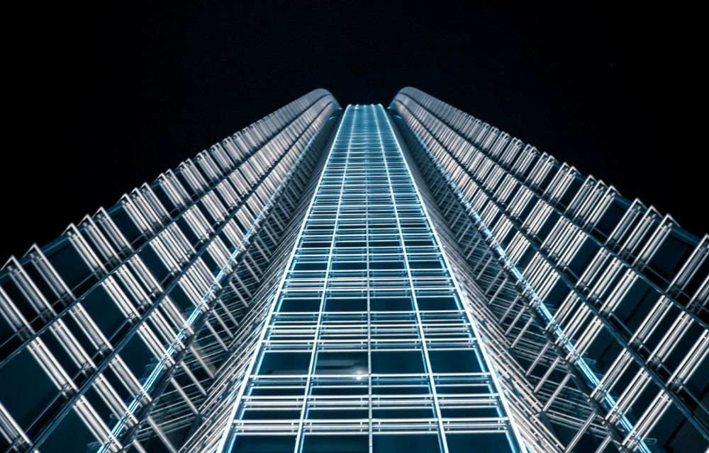 nighttime view from below of the tall business center with light blue illumination
